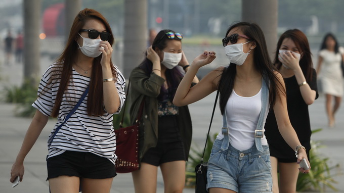 Shoppers wearing face masks walk to The Shoppes at Marina Bay Sands on a hazy day in Singapore June 19, 2013. Singapore's worst air pollution in 16 years sparked diplomatic tension on Tuesday, as the city-state urged Indonesia to provide data on company names and concession maps to enable it to act against plantation firms that allow slash-and-burn farming. REUTERS/Edgar Su (SINGAPORE - Tags: ENVIRONMENT)