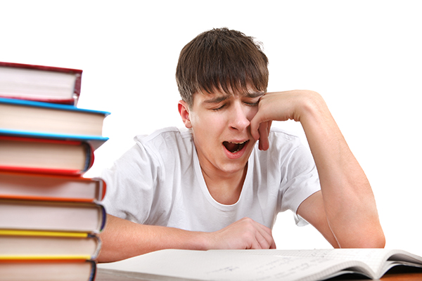 Tired Student Yawning on the School Desk Isolated on the White